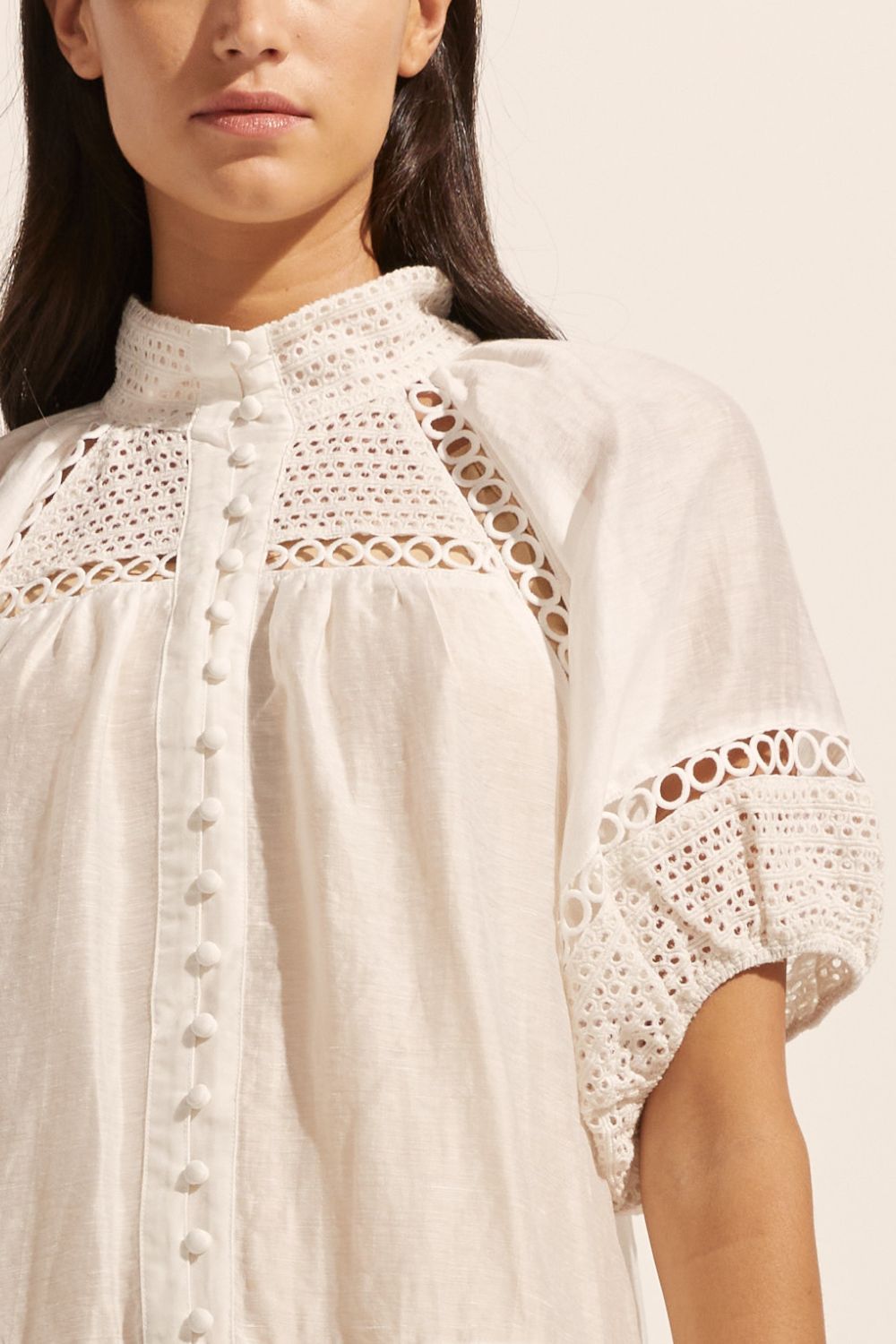 white, high neck, covered buttons, circular lace detailing, drop waist, mid-length sleeve, mini dress, close up image